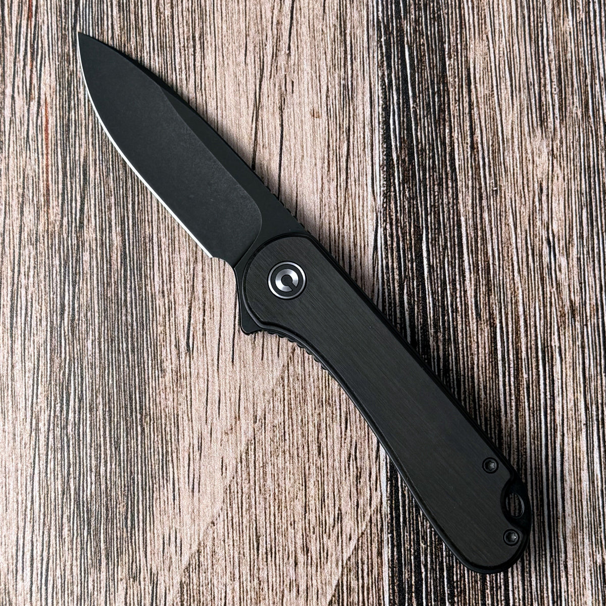 Civivi Elementum with ebony-wood handle and open black stonewashed blade on a wood surface